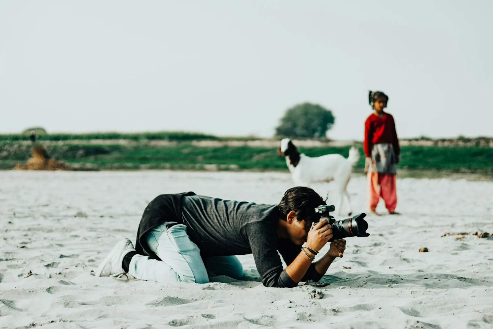 A photographer lying on the sand with a camera