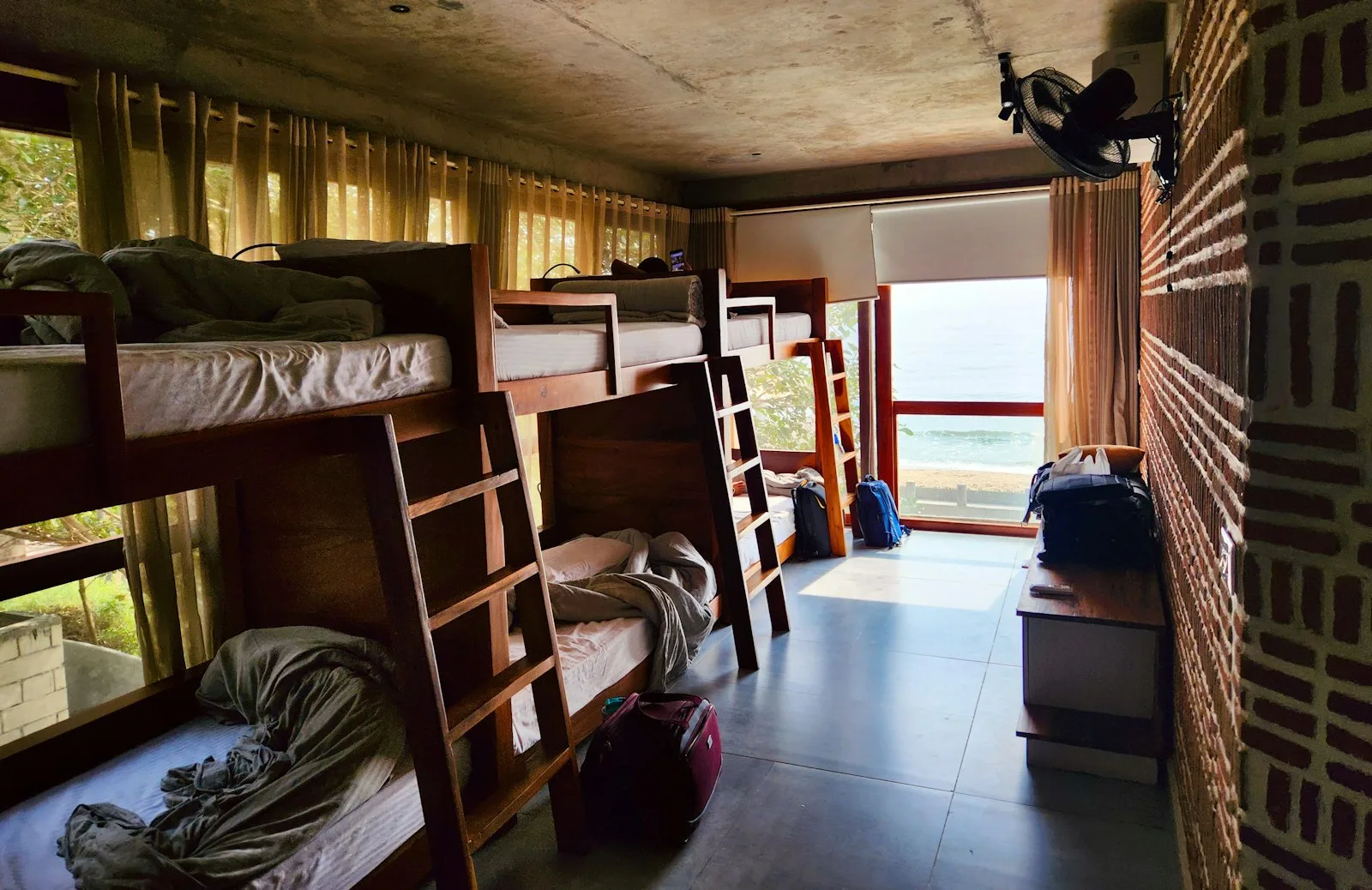 A hostel room with bunk beds by a window